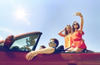 leisure, road trip, travel and people concept - happy friends driving in cabriolet taking selfie by smartphone outdoors. friends driving in cabriolet car and taking selfie. friends driving in cabriolet car and taking selfie