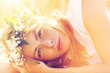 nature, summer holidays, vacation and people concept - face of happy woman in wreath of flowers lying on cereal field. happy woman in wreath of flowers on cereal field. happy woman in wreath of flowers on cereal field