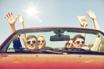 leisure, road trip, travel and people concept - happy friends driving in cabriolet car at country and waving hands. happy friends driving in cabriolet car at country. happy friends driving in cabriolet car at country