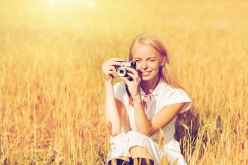 nature, summer holidays, vacation and people concept - happy woman taking picture with film camera outdoors. happy woman with film camera in wreath of flowers. happy woman with film camera in wreath of flowers
