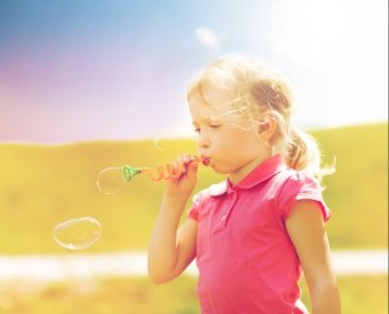summer, childhood, leisure and people concept - little girl blowing soap bubbles outdoors. little girl blowing soap bubbles outdoors. little girl blowing soap bubbles outdoors