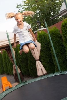 Girl enthusiastically jumping on the trampoline. Moment flight. Girl is jumping on batut