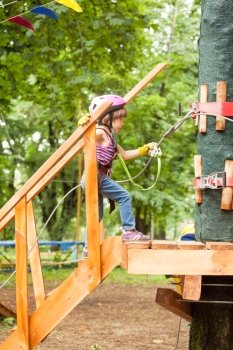 Kids on obstacle course in adventure park in mountain helmet and safety equipment. The obstacle course in adventure park 