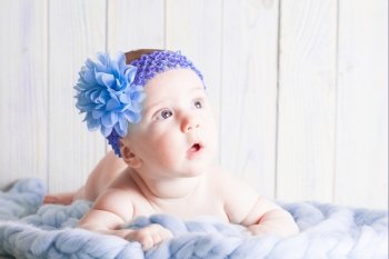 Naked baby girl lying  on the soft curtain with violet headband around her head. Cute baby girl 