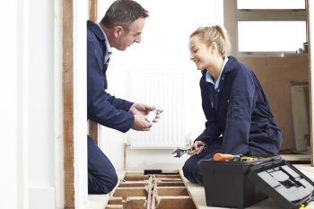 Plumber And Female Apprentice Fitting Central Heating