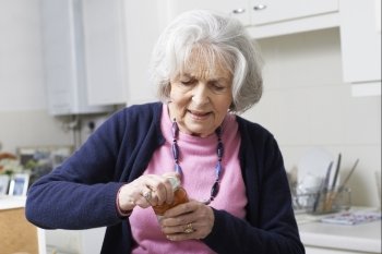 Senior Woman Struggling To Take Lid Off Jar