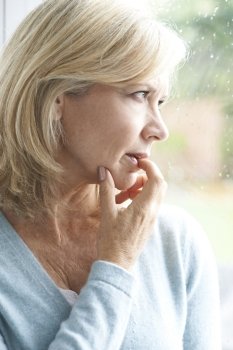 Sad Mature Woman Suffering From Agoraphobia Looking Out Of Window