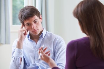 Depressed Young Man Talking To Counsellor