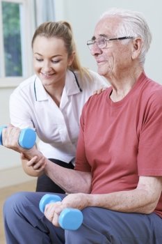 Senior Male Working With Physiotherapist Using Weights