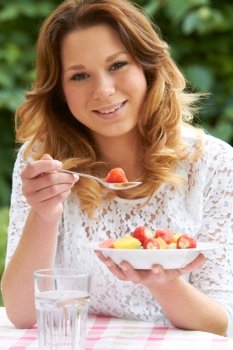 Teenage Girl Eating Healthy Bowl Of Fruit Salad