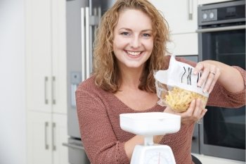 Plus Size Woman On Diet Weighing Out Pasta For Meal