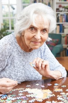 Senior Woman Relaxing With Jigsaw Puzzle At Home