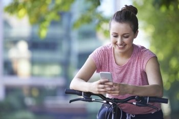 Young Woman Using Mobile Phone Whilst Out On Cycle Ride