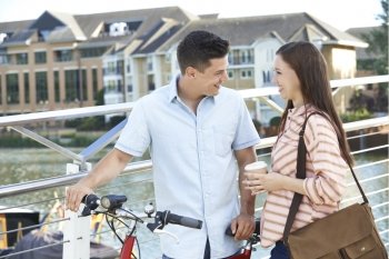 Young Couple Walking And Cycling To Work In Urban Setting