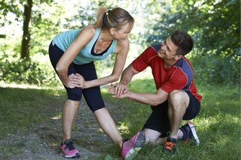 Mature Woman Exercising With Personal Trainer In Park