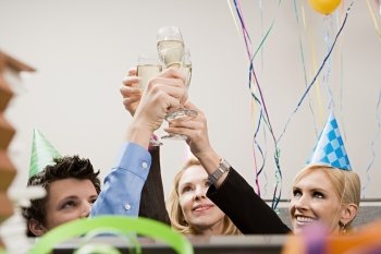 Three office workers toasting with champagne