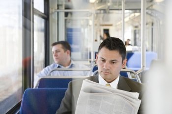 Businessman reading newspaper on train