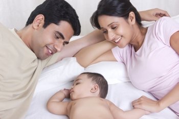 Mother and father watching baby sleep