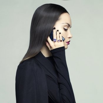 Fashion portrait of stylish woman in black cape talking on her mobile phone. Perfect makeup and manicure. Rings with precious stones