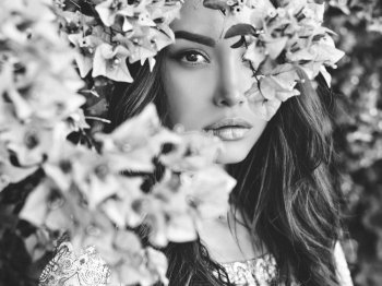 Black and white Outdoor fashion photo of beautiful young woman surrounded by flowers. Spring blossom