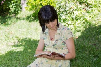 beautiful young woman reading book at park