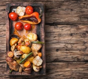 Baked meat with vegetables. Meat baked with potatoes and mushrooms on vintage wooden background