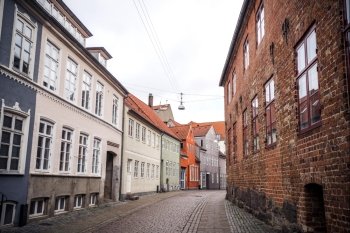 Old buildings on a street in Denmark with an orange painted house at the end of the street