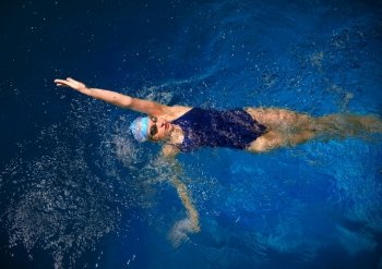 Young woman swimmer in blue pool water
