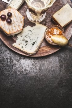 Wine and cheese on dark rustic background, top view, border