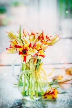 Red and yellow tulips bunch in glass vase at window with spring nature. Parrot tulips bouquet