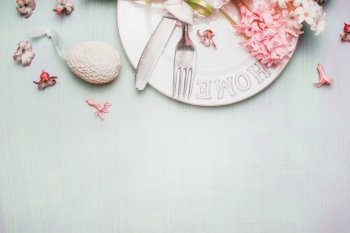 Easter border with table place setting with decor egg and flowers on  light pastel wooden background, top view, place for text