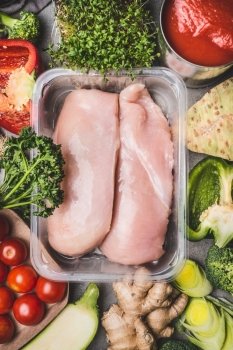 Raw organic chicken breast fillets in plastic packaging tray with various vegetables for tasty cooking, top view. Healthy food and Sports or diet nutrition concept