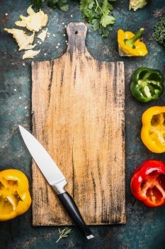 Blank aged wooden cutting board with kitchen knife and  Bell colorful paprika peppers , top view