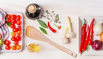 Healthy cooking with various fresh spices: olive oil, chili, onion, garlic and Bay leaves on white wooden background, top view