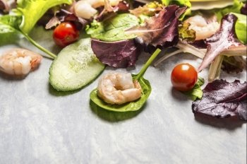 Colorful fresh salad with cucumber and shrimps, close up, place for text