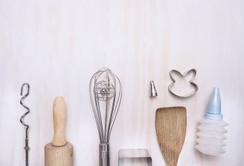 Baking set utensils with rolling pin, spatula, whisk, slotted wooden spoon on white wooden background, top view, place for text
