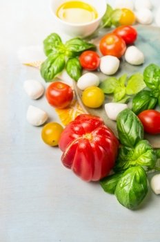 Tomatoes various with fresh basil and mozzarella on blue wooden background