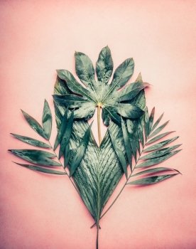 Creative Bunch of various tropical palm leaves  on pastel pink background, top view