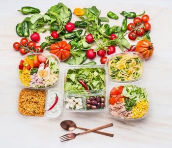 Healthy food concept. Variety of clean dieting salad bowls and vegetables with cutlery on white wooden background, top view, copy space. Various fresh vegetable salads in  plastic package .