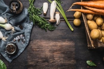 Autumn seasonal  cooking ingredients with harvest vegetables, greens , Potatoes and mushrooms on dark rustic wooden background, top view, place for text, border