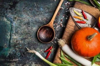 Pumpkin cooking on rustic kitchen table background with ingredients and wooden cooking spoon, top view, place for text