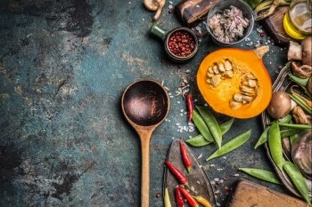 Thanksgiving seasonal cooking with Healthy and organic harvest vegetables and ingredients: pumpkin, Pea,chili,Mushrooms with wooden cooking spoon on rustic kitchen table background , top view