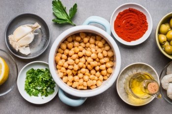 Cooking ingredients in bowls for Chickpea salad on gray concrete background, top view, close up. Healthy , clean food or vegetarian cooking and eating concept