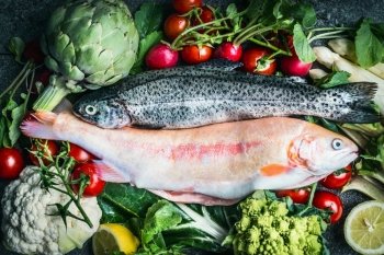 Two raw Trout fishes with fresh vegetables ingredients for healthy clean cooking, top view