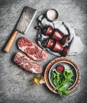 Raw fresh marbled meat Steak with meat cleaver seasonings on dark  rustic concrete background, top view. Meat cooking preparation