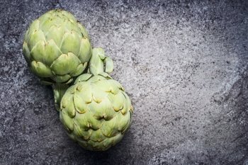 Green Artichokes  on gray concrete background, top view. Superfood concept