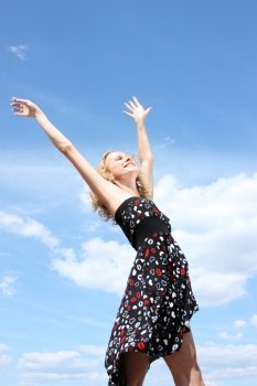 Young woman in summer dress on a background of the blue sky 
