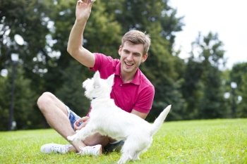 Young man playing with his dog in the summer park