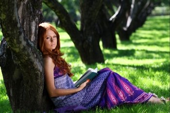 young woman in summer, green park reading book