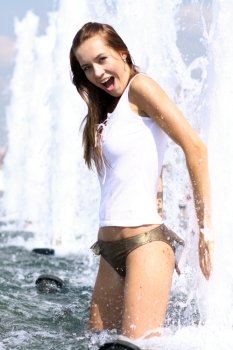 Young sexy woman bathes in a city fountain 